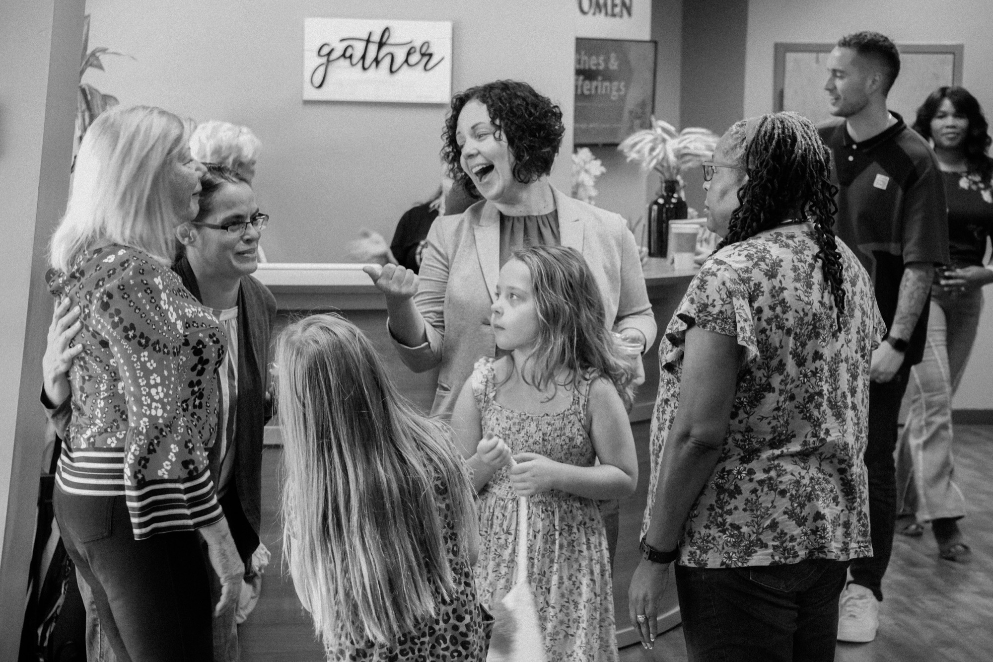 Women and children greeting in a room with a gather sign